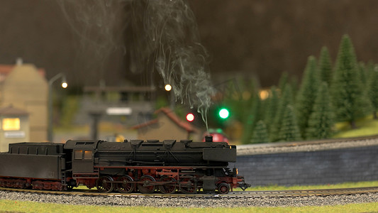 一辆模型火车在森林中的户外轨道上行驶。