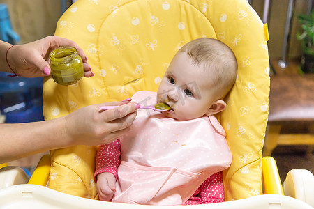 宝宝穿棉衣服摄影照片_妈妈给宝宝喂蔬菜泥。