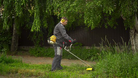 一名来自特种部队的年轻人正在用汽油修剪机修剪草坪。