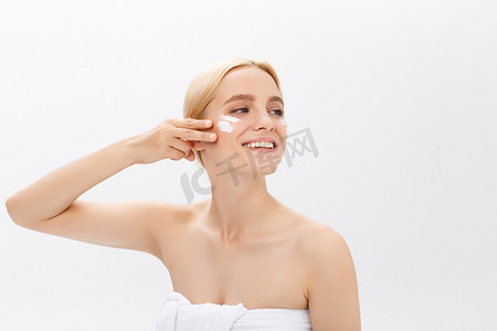 美丽的模特在白色的脸上应用美容霜治疗