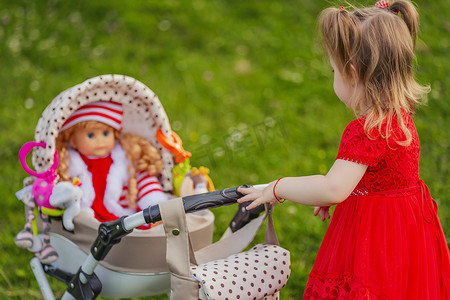 女孩正在玩她坐在婴儿车里的洋娃娃