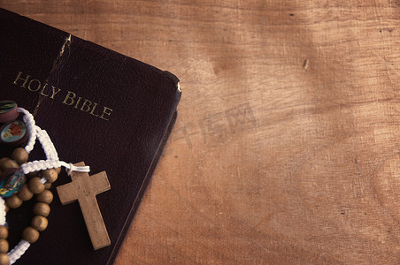 圣经和念珠放在木桌上，可定制空间来添加想法或文字。