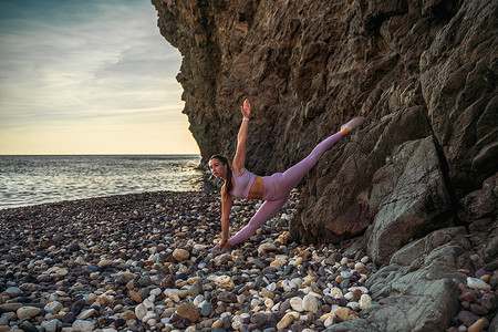 海边女子摄影照片_女子体操运动员正在海边训练。