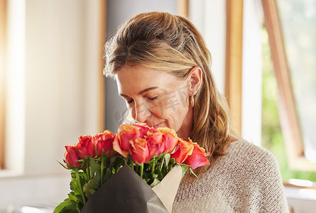 成熟的女人，在房子或家里的情人节、生日和庆祝活动中散发香味和闻​​玫瑰。