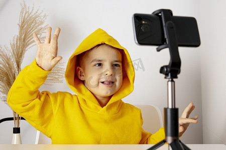 可爱、可爱的小男孩博主记录生活方式博客，与三脚架上的智能手机相机交谈。