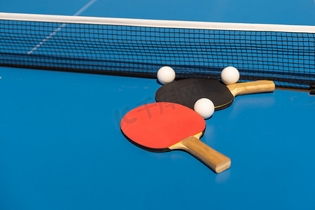 体育馆里的乒乓球桌、球拍和球。