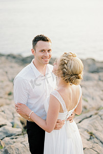 搂腰摄影照片_新郎站在岩石上搂着新娘的腰