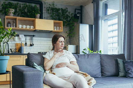 生病的孕妇坐在家里的沙发上