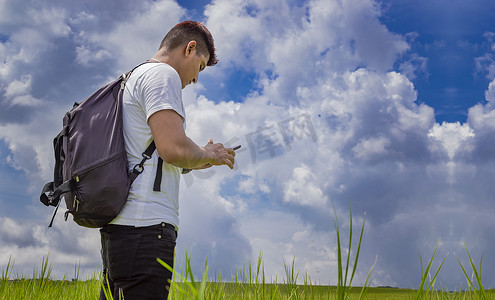 男子用手机打电话，年轻人在现场用手机打电话，年轻背包客在现场用手机和复印空间