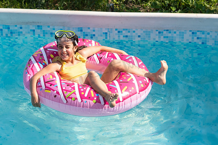 阳光明媚的日子，在室外游泳池里微笑着可爱的白人小女孩。