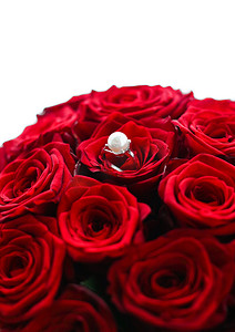 美丽的白金珍珠戒指和红玫瑰花束、奢华珠宝情人节和浪漫假期的爱情礼物