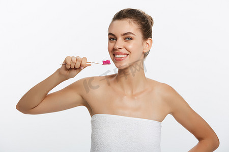 一位快乐美丽的半裸女人用牙刷刷牙，看着白色背景中突显的相机的美女肖像