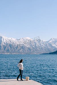 孕妇站在山海背景下的码头上