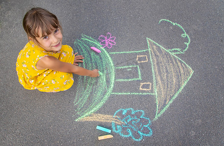 孩子在柏油路上画了一栋房子。