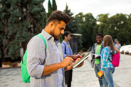 智能社区摄影照片_印度学生站在户外，手里拿着一摞书