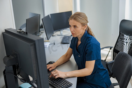 现代诊所接待台的值班护士在电脑上工作