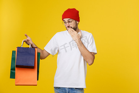 留着胡子的男人，提着购物袋，在黄色的免费场地上感到快乐