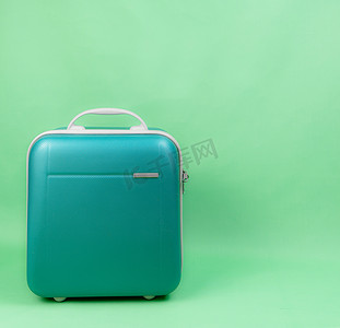 绿色背景下旅行的绿色行李箱