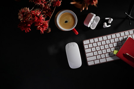 键盘耳机鼠标摄影照片_黑色背景中配有耳机、无线键盘、鼠标、笔记本和咖啡杯的顶视图时尚工作场所