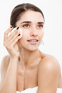 美容护肤概念-美丽的女人用棉签清洁她的脸-在白色背景和微笑。