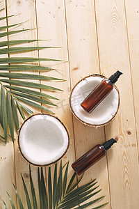 热带叶子、护理化妆品和椰子在木桌上。