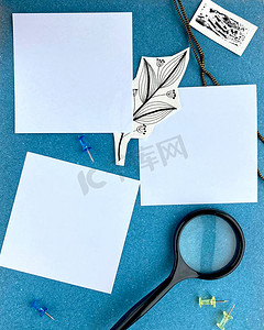 蓝色背景空纸提醒上的明信片模型或带有放大镜邮票和剪纸涂鸦分支手绘的列表纸。