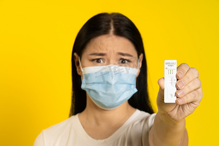 显示阳性测试害怕戴医用口罩冠状病毒或猴痘预防的大流行成熟亚洲女性。