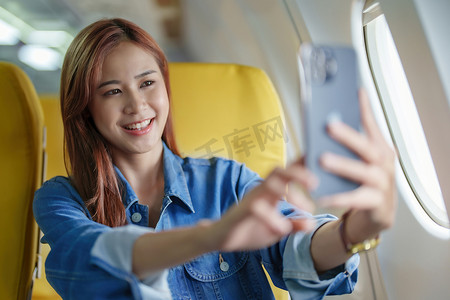 旅行、旅游业务、一名女性在飞机上用手机自拍发布自己的个人资料照片的肖像
