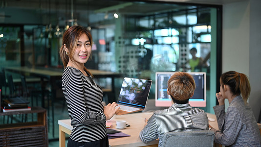 软件工程师团队领导站在笔记本电脑上，对着镜头微笑。
