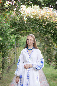 公园户外身穿蓝色民族传统刺绣衬衫的乌克兰年轻女子肖像