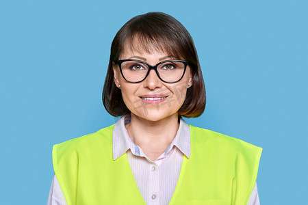 蓝色孤立背景中戴着防护背心眼镜的工业成熟女性的头像