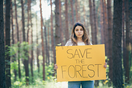 森林里年轻漂亮的女志愿者活动家，张贴着拯救森林的海报