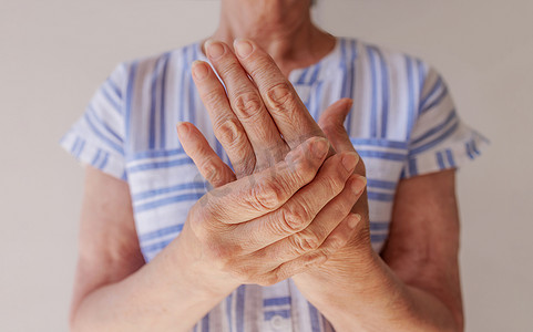 一位手部疼痛的老妇人摩擦手腕，特写
