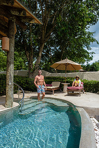 欧洲男人和亚洲女人在无边泳池，泰国豪华度假，私人泳池别墅