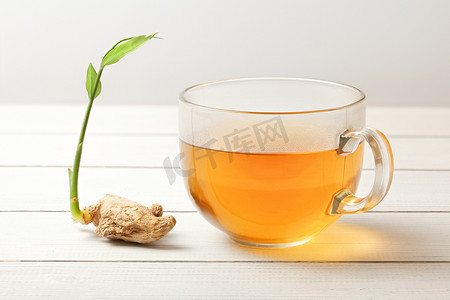一杯姜茶（热蒸汽和水滴在玻璃上），干根，旁边有绿色的泉水。