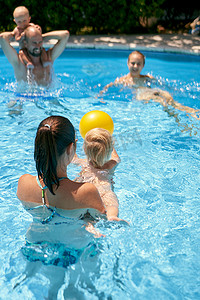 玩球小孩摄影照片_有小孩在游泳池里玩球的父母