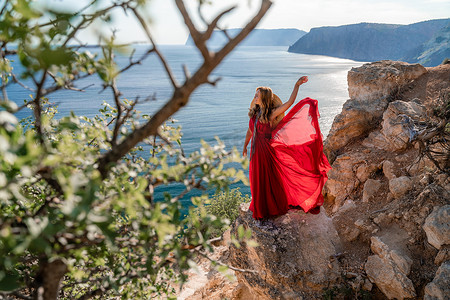 大海背景下，身穿飞扬红裙、头戴草帽的女子随风飘扬。