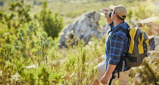活跃的成熟男人背着背包，在外出远足时喝水瓶，白天探索大自然并得到良好的锻炼