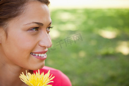 花朝摄影照片_拿着一朵黄花朝侧面看的女人