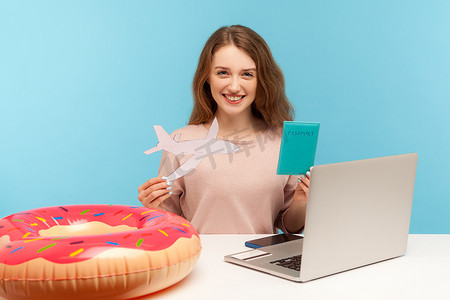签证飞机摄影照片_在蓝色背景上使用笔记本电脑的情感年轻女子。