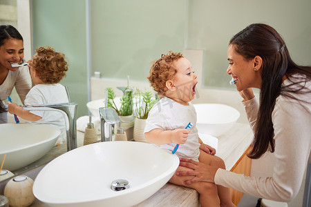 海棉宝宝摄影照片_妈妈在家里的浴室柜台上教宝宝刷牙，脸上挂着干净的笑容。