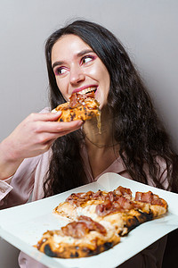 女孩快递员在灰色背景下吃 Pinsa 罗马披萨美食意大利美食。