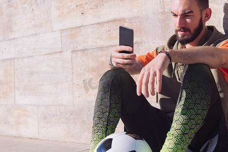 足球运动员休息时咨询他的智能手机