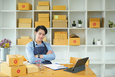 一家小型初创企业和中小企业主的照片，一位亚洲男性企业家检查订单以整理产品，然后将其装入内盒供客户使用