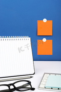 重要信息写在桌子上的笔记本上，配有铅笔、键盘、笔记和眼镜。
