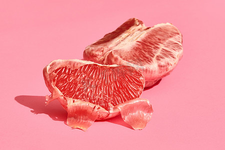 粉红色背景上去皮多汁葡萄柚片的高质量图像特写