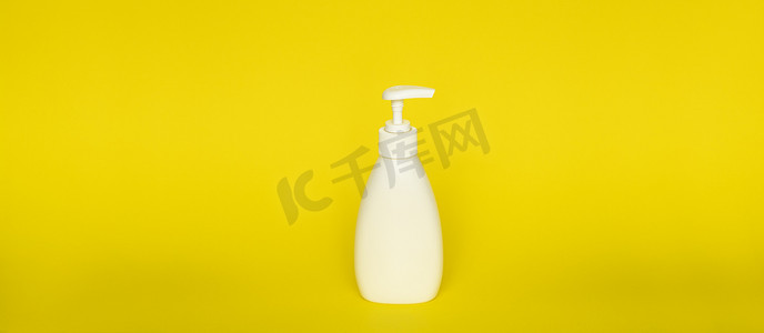有泵分配器的大白色塑料瓶在黄色背景。