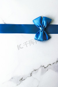 豪华大理石背景上的蓝色丝带和蝴蝶结、假日平底背景