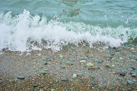 海岸有卵石、海滩上湿海卵石和安静的海浪