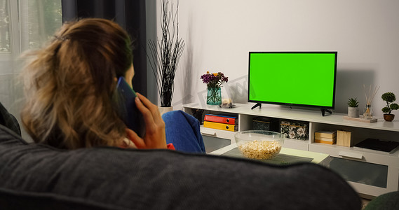 女人看电视绿色色度键屏幕并打电话。